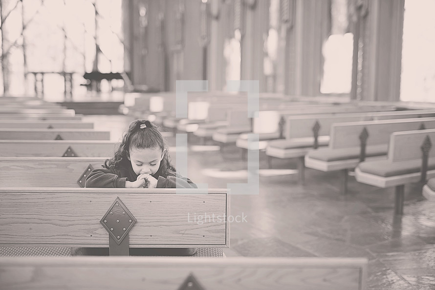 a girl child in prayer in a church 