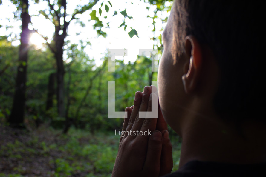boy praying in a forest 
