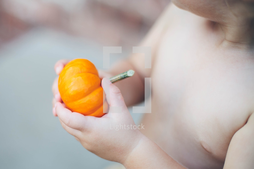 a toddler boy holding a pumpkin 