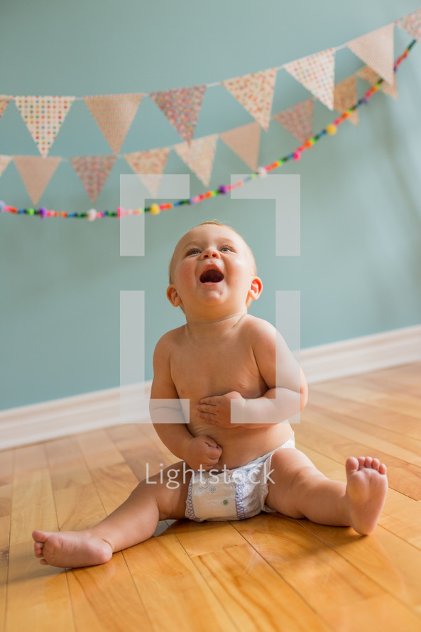 an infant in diapers under a banner 