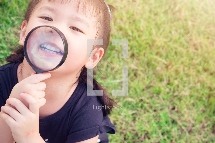 child looking through a magnifying glass 