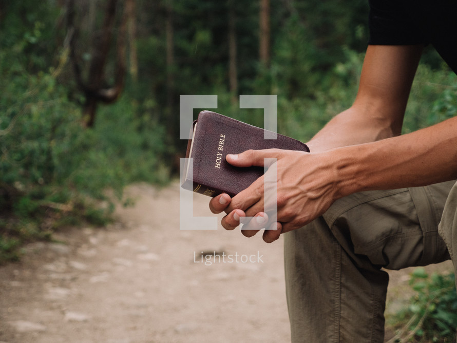 man holding a Bible outdoors 