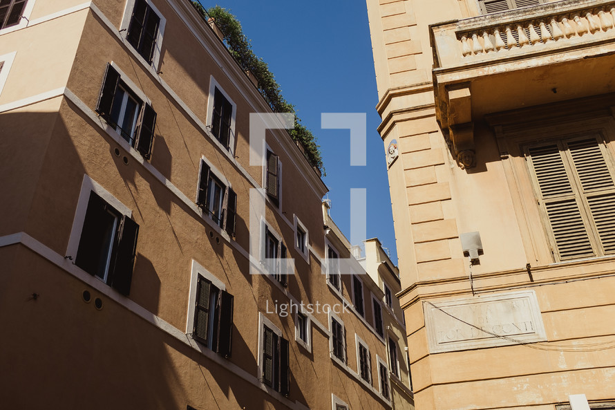 windows on the sides of buildings lining the narrow streets of Rome 