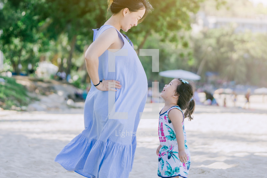 pregnant mother and toddler daughter on a beach 