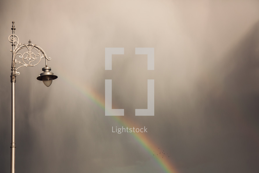 street light and rainbow against gray clouds 