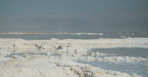 Close up of salt deposits on the banks of the Dead Sea in Israel. The Dead Sea and the Jordanian mountains in the background