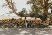 a woman on a bicycle in front of a stacked stone fence 