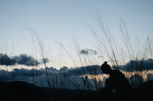 silhouette of a woman sitting outdoors at sunset 