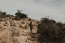 a man with a camera walking up a rocky slope 