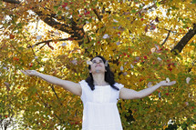 a woman tossing fall leaves 