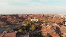 Aerial footage flying towards a large palace, brightly lit by by a sunset, on top of a hill of Jodhpur, India. 