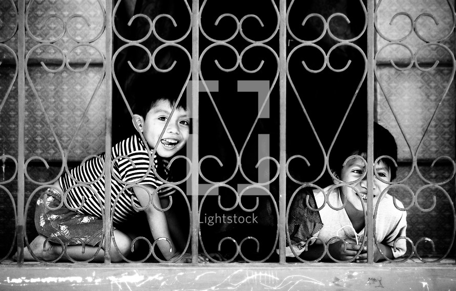 Boys playing behind chain window/fence