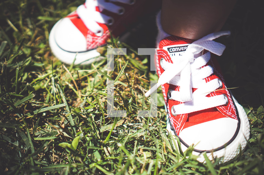 red sneakers on a toddler standing in the grass