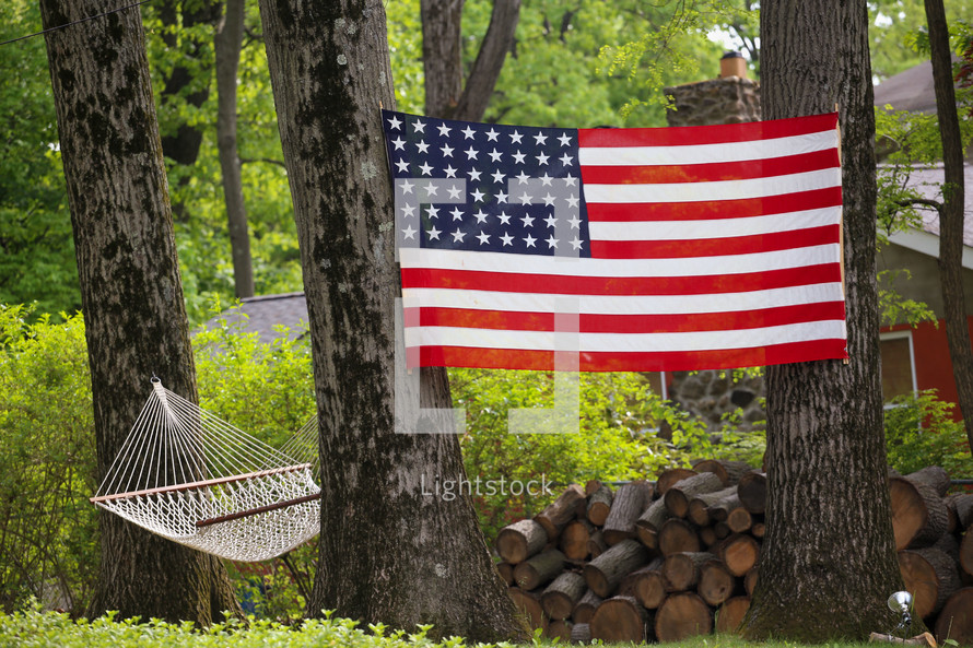 hammock, firewood, and American flag between trees