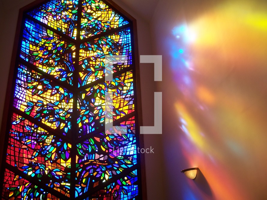 The Window to Heaven - a stained glass window in a small chapel reflects the light and love of Heaven radiating light as a prism on the walls of the church chapel. 