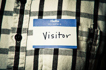 man wearing a name tag with the word visitor 