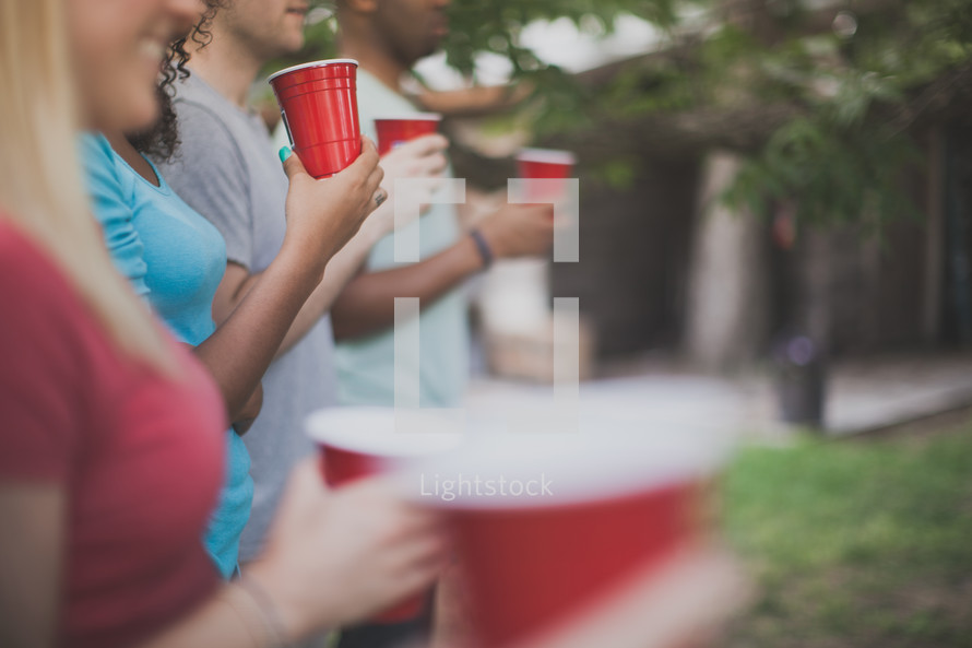 friends holding red cups at a cookout 