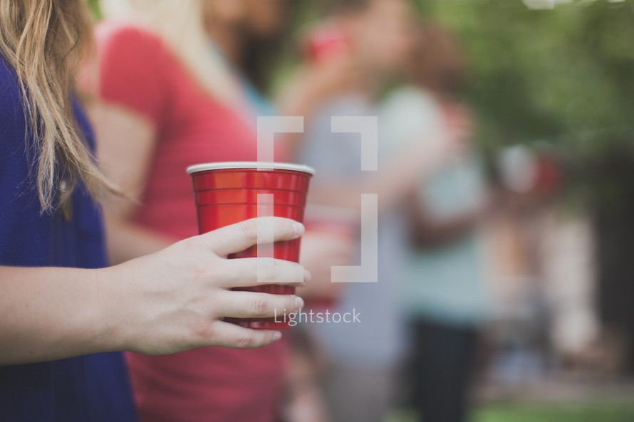 friends holding red cups at a cookout