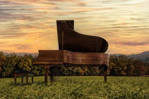 grand piano in a field at sunset 