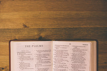 Bible open to The Psalms on a wooden table.