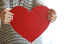 a woman holding a red paper heart 