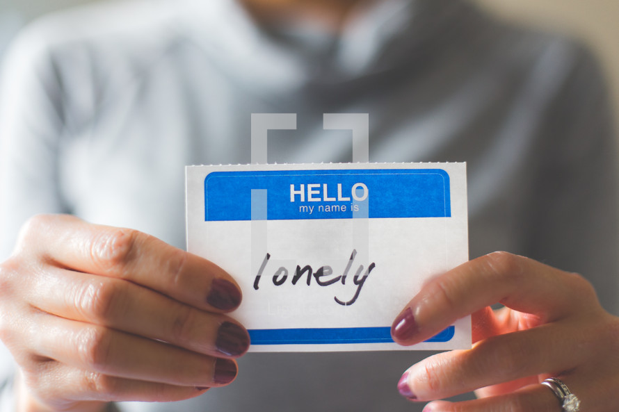 woman holding a name tag with the word lonely 