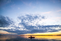 man in a canoe on a lake at sunset 