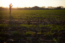 silhouette of a man praying in a field under the glow of sunlight