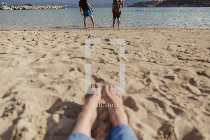 men standing on a beach in Greece and feet in the sand