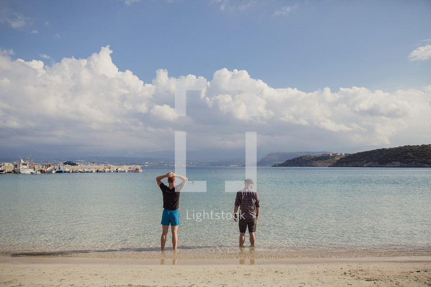 men standing in water on a beach in Greece 