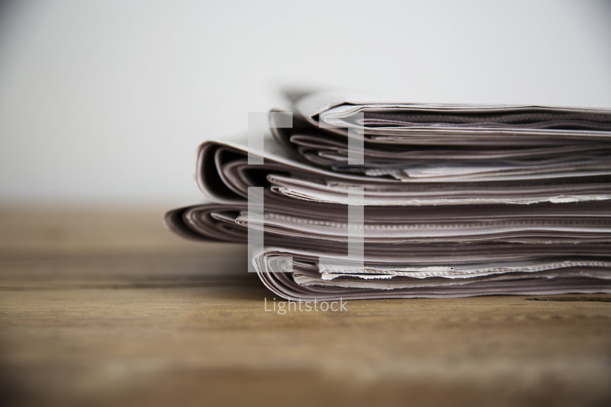 stack of newspapers on a wood table. 