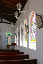 A church sanctuary with stained glass windows and wooden pews.