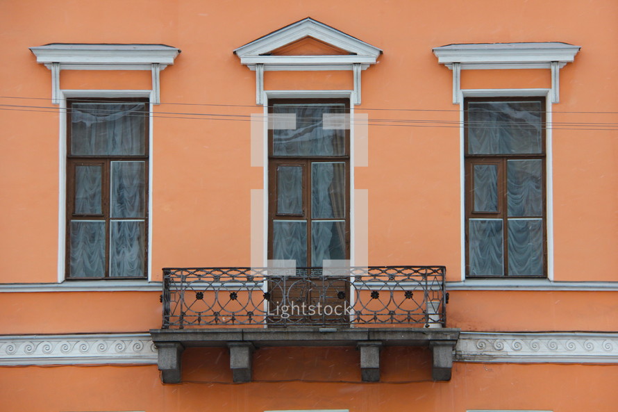 Side of a building with three windows and a balcony.