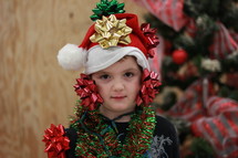 Boy covered in Christmas decorations.