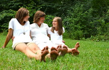 mother and daughters sitting with their feet in the grass 
