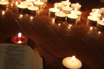 Bible in front of burning votive candles