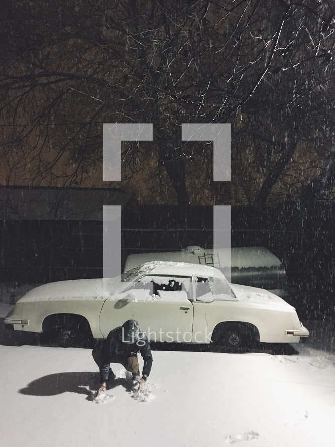 man playing in snow and car