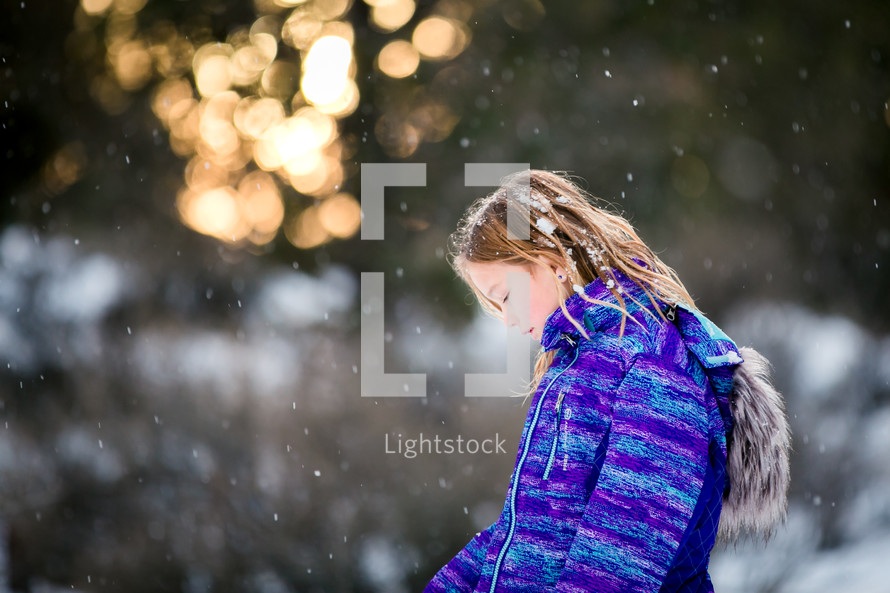 a girl child in a winter coat standing outdoors in snow 
