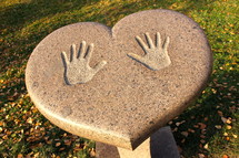 Handprints on a heart shaped table outdoors at a park.