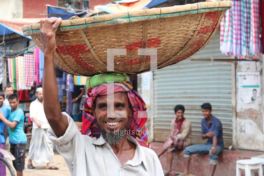 Bangladeshi man with a basket on his head in the market 