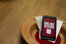 offering plate with a cellphone with an online giving app on the screen 