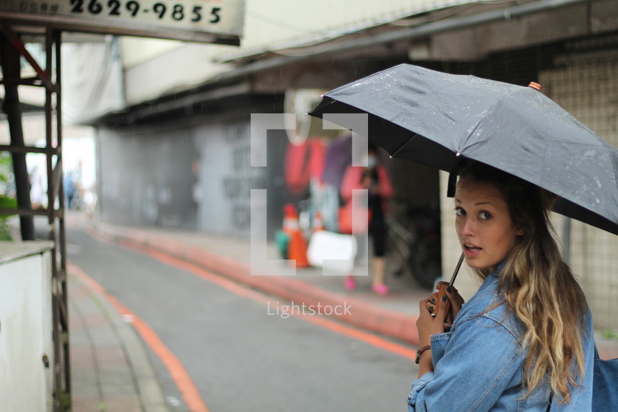 a woman with an umbrella walking down the street 