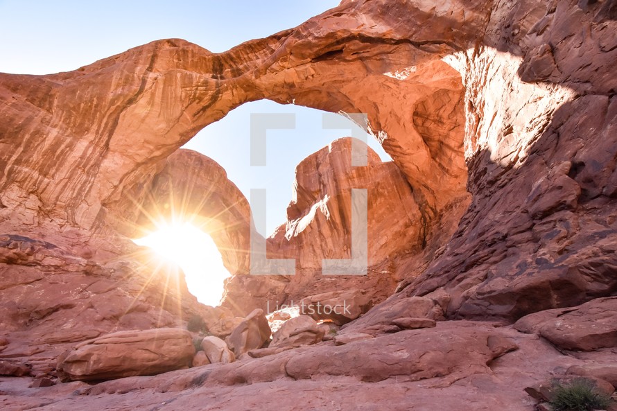 sunburst through a red rock arch 