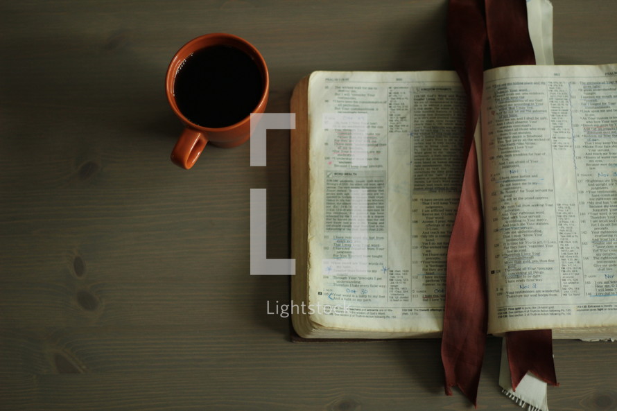 an open Bible and coffee mug on a coffee table