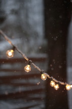 falling snow and a string of glowing lightbulbs