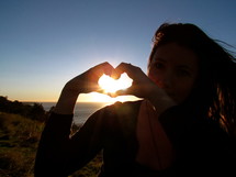 teen girl making a heart with her hands 
