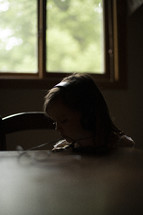 a girl sitting at a table listening to headphones 