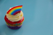 Cupcake decorated with cream cheese and a fondant rainbow