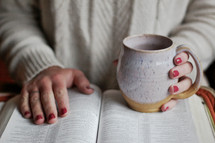 a woman reading a Bible holding a coffee mug 