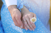romantic date concept. young man and woman hands holding each other. girl with golden ring on finger in blue dress with chamomile flower in hand.